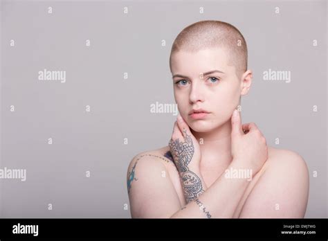 A Young Woman With A Shaved Head And Tattoos On Her Shoulder Arms And