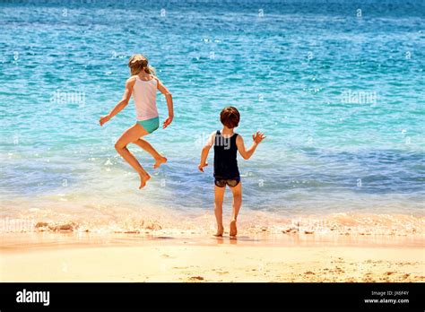 Dos Niños Jugando Saltando En Las Olas Del Mar En Una Playa De Arena En