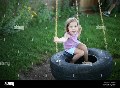 Portrait Of Young Girl On Tire Swing In Backyard Stock Photo Alamy