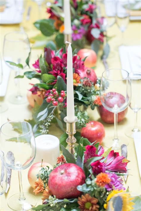 the table is set with flowers apples and candles for a festive dinner party