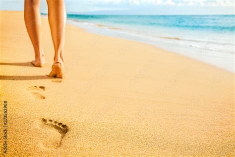 beach woman legs feet walking barefoot on sand leaving footprints on golden sand in sunset