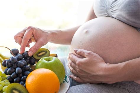 A Pregnant Woman With Belly Holding A Plate With Fruits Concept For