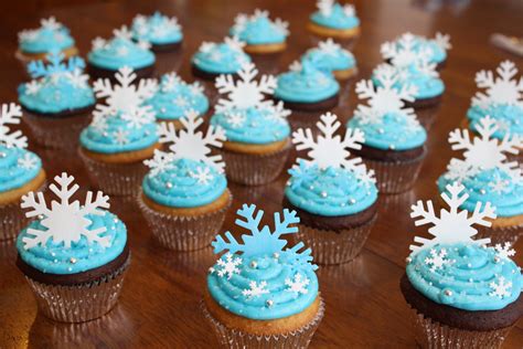 Cupcakes With Blue Frosting And White Snowflakes On Them Sitting On A Table
