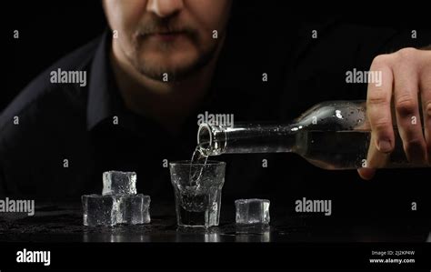 Bartender Man Pouring Up Frozen Vodka Sake From Bottle Into Shot Glass