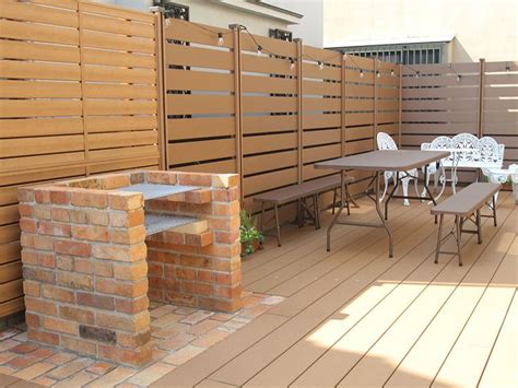 A Wooden Deck With Tables And Chairs Next To A Fence