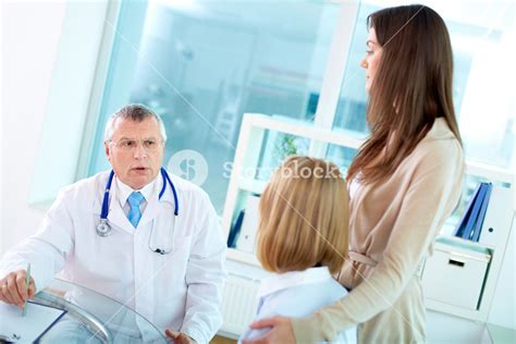 Portrait Of Two Female Patients And Mature Doctor Interacting At