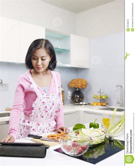Asian Housewife Wearing An Apron And Standing To Washing Lettuce And