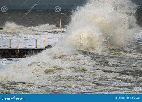Breakwater And Harbour In Stormy Weather With Huge Waves Crashing Over