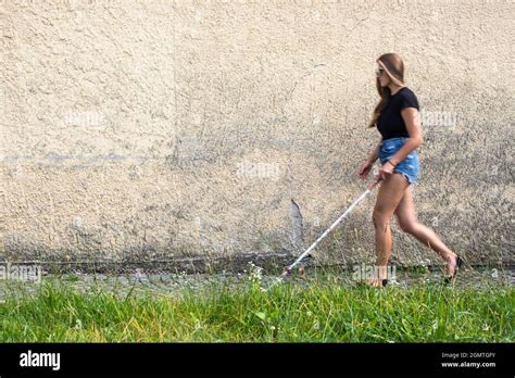 Blind Woman Walking On City Streets Using Her White Cane To Navigate