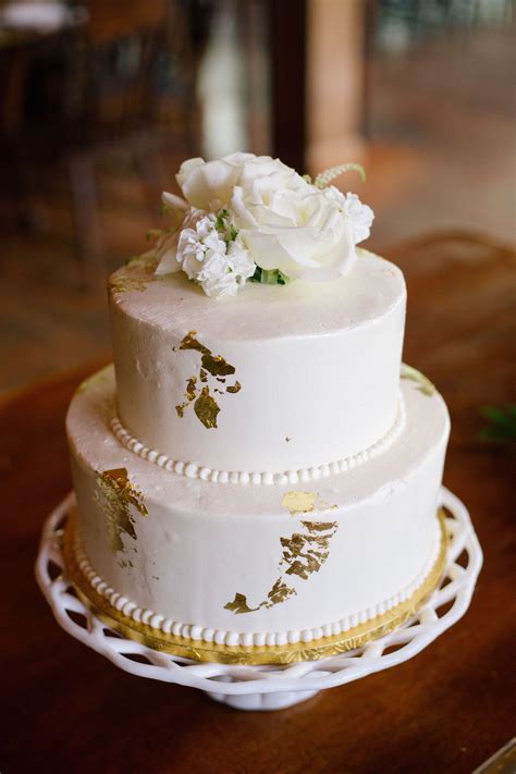 Simple White Frosted Wedding Cake With Gold Details Topped With White