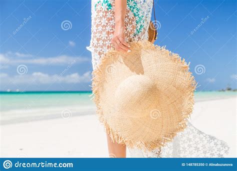 Tanned Girl In Blue Bikini And White Tunica Holding Big Straw Hat On