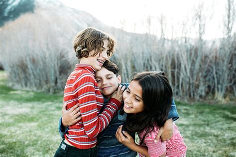little brother hugging two sisters one wants to get away photograph by cavan images fine art