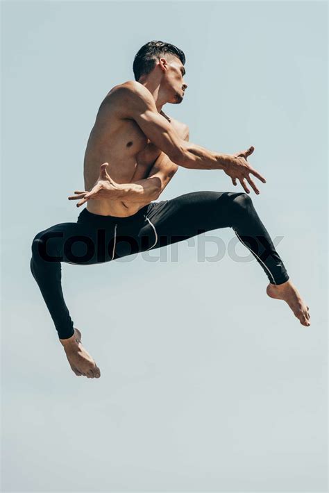 Motion Shot Of Attractive Shirtless Dancer In Jump Against Blue Sky