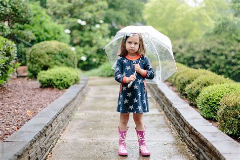 Cute Young Girl Standing In The Rain With An Umbrella Del Colaborador De Stocksy Jakob