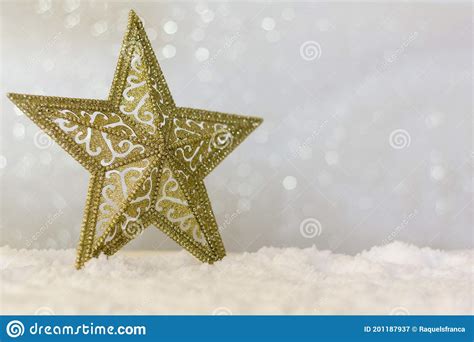 Golden Christmas Star On Snow With Sparkle Bokeh Background With Copy