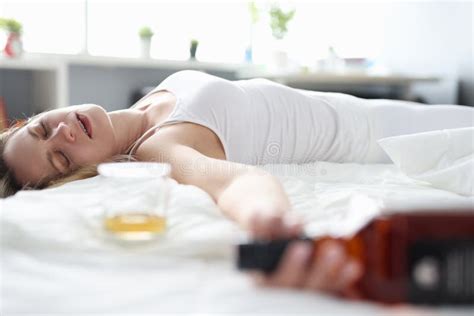 Young Woman Lying In Bed With Bottle Of Alcohol And Glass Stock Image