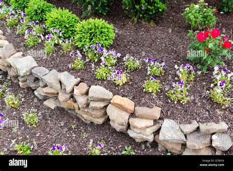 Natural Rock Retaining Wall In A Garden With Rough Rocks And Stones