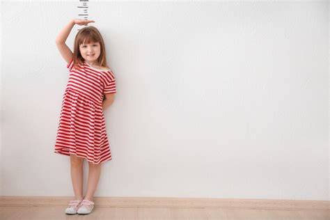 Premium Photo Cute Little Girl Measuring Height Near Light Wall
