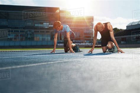 Young Athletes Preparing To Race In Start Blocks In Stadium Sprinters