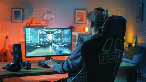Back shot of a gamer playing first-person shooter online video game on ...