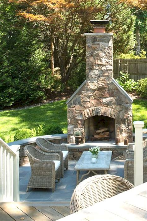 An Outdoor Fireplace With Wicker Chairs Around It And A Table On The