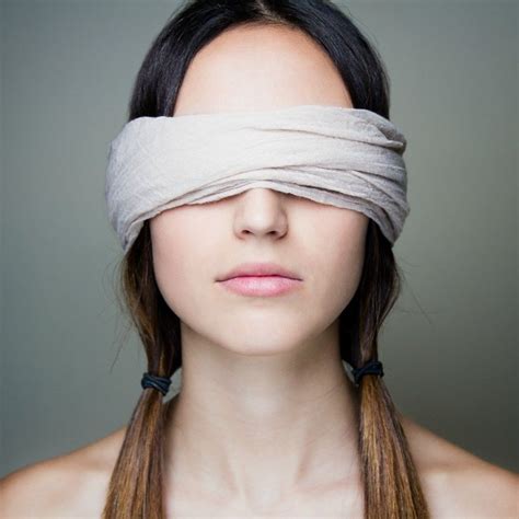 a woman with blindfold on her face and hair tied to her forehead looking at the camera