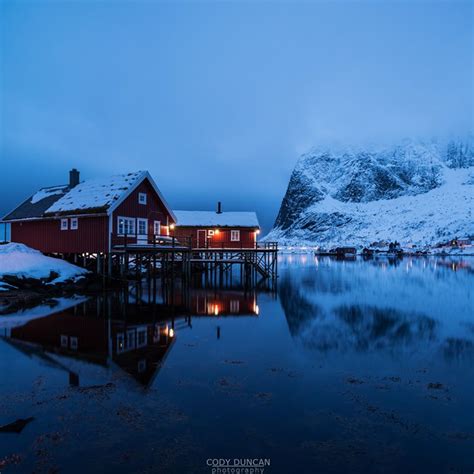 Traditional Rorbu Cabin Reflects In Fjord In Evening Light Valen