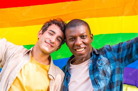 premium photo portrait of multiethnic gay male couple holding a rainbow lgbt symbol flag