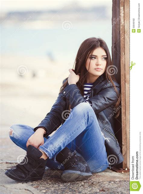 Portrait Of A Young Woman Sitting On The Sidewalk Stock