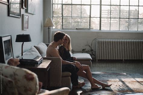 Young Couple Sitting Together Hugging On Couch In Industrial Loft By Stocksy Contributor Jess