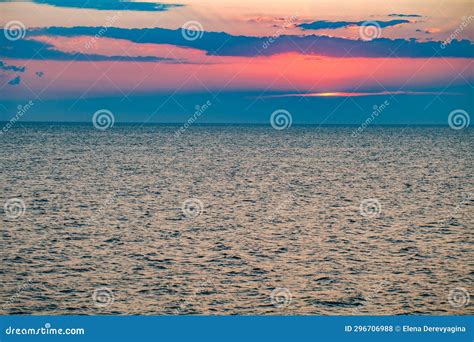 Sunset Over Water Surface Of Sea And Red Sun In Clouds Above Horizon