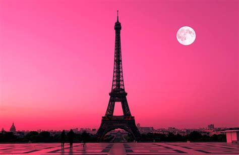 The Eiffel Tower Is Lit Up In Pink And Purple Colors At Night Time