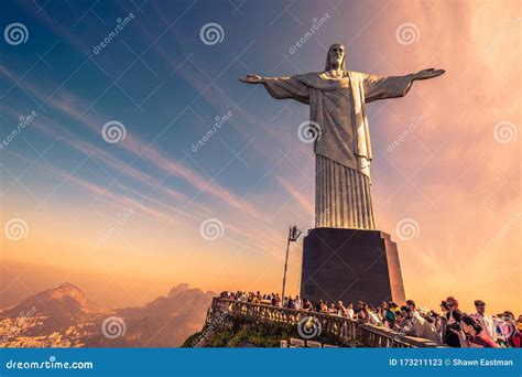 Christ The Redeemer Statue At Sunset With Tourists On Top Of Mount