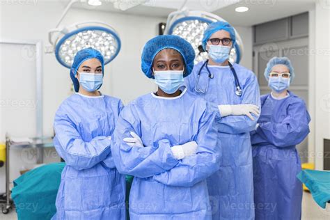 Group Of Medical Surgeons Wearing Hospital Scrubs In Operating Theatre