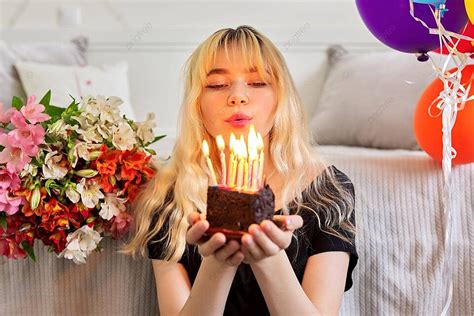 فتاة مراهقة تحتفل بعيد ميلادها مع كعكة صغيرة وتحترق الشموع صورة الخلفية والصورة للتنزيل المجاني