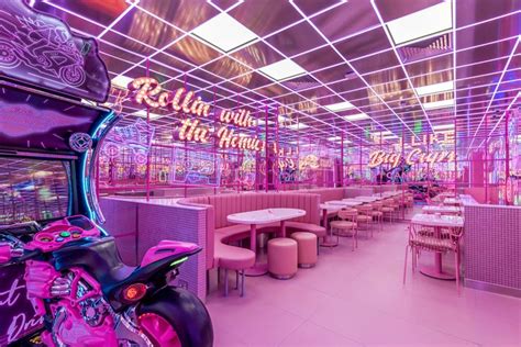 The Interior Of A Restaurant With Neon Lights And Pink Furniture