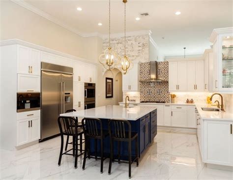 A Large Kitchen With White Cabinets And Marble Counter Tops An Island