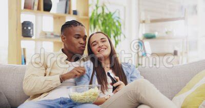 Couple Popcorn And Watching Tv In Home Pointing And Bonding On Sofa