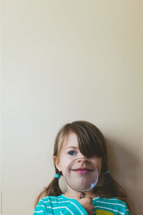 Young Girl Grins While Holding Magnifying Glass By Stocksy Contributor Amanda Worrall Stocksy