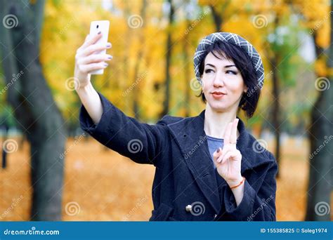 Beautiful Woman Taking Selfie By Smartphone And Having Fun In Autumn City Park Fall Season