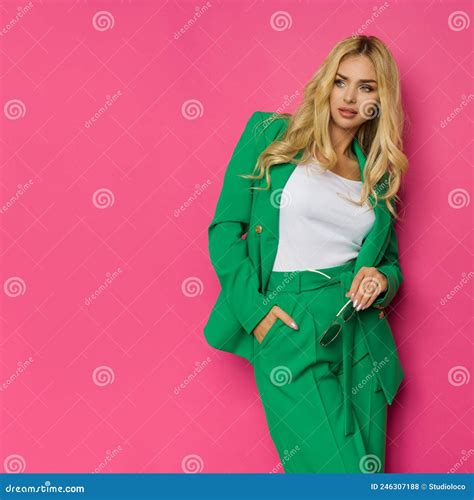 Beautiful Blond Woman In Unbuttoned Green Jacket And Pantsuit Is Posing