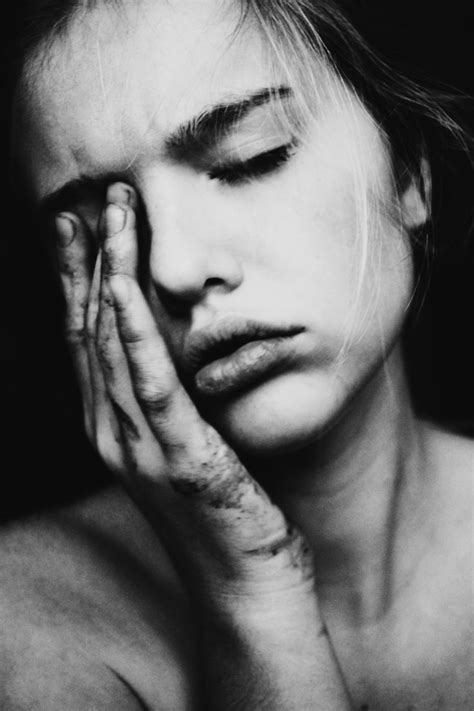 A Black And White Photo Of A Woman Holding Her Hand To Her Face With