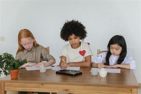 Multiethnic cute little girls painting on papers sitting at desk in ...