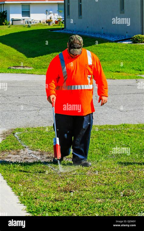 Highway Maintenance Worker Wearing An Orange Safety Jacket Using A