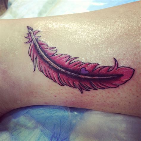 A Tattoo With A Red Feather On The Side Of Someones Leg That Is