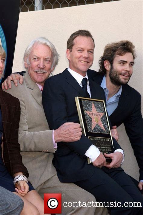 Three Men In Suits And One Is Holding A Star