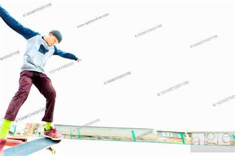 A Young Teenager A Skateboarder Does A Trick On The Railing In A
