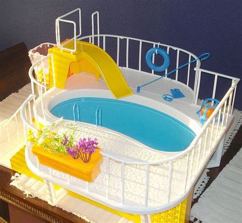 A Toy Swimming Pool With A Slide And Flower Pots On The Table Next To It