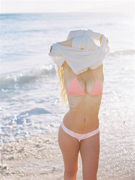 Girl In Bikini Taking Shirt Off At Beach With Ocean By Stocksy