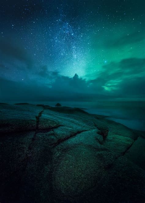 The Night Sky Is Filled With Green And Blue Lights As Well As Stars Above